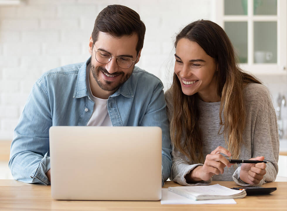 lächelnde Frau und Mann, die den Bildschirm eines Laptops anschauen, die Finanzen überprüfen, gemeinsam am Tisch sitzen
